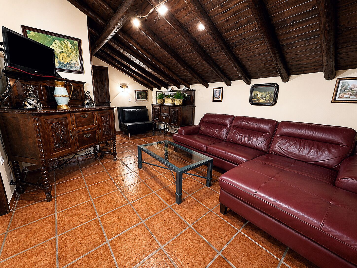 A living room with a red leather sofa, wooden cabinet, and a glass coffee table.