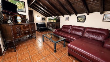 A living room with a red leather sofa, wooden cabinet, and a glass coffee table.