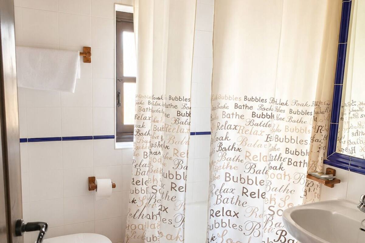 A bathroom with a shower curtain, toilet, sink, and a towel rack.
