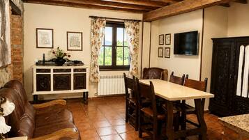 A dining area with a wooden table and chairs, a fireplace, and a window with curtains.