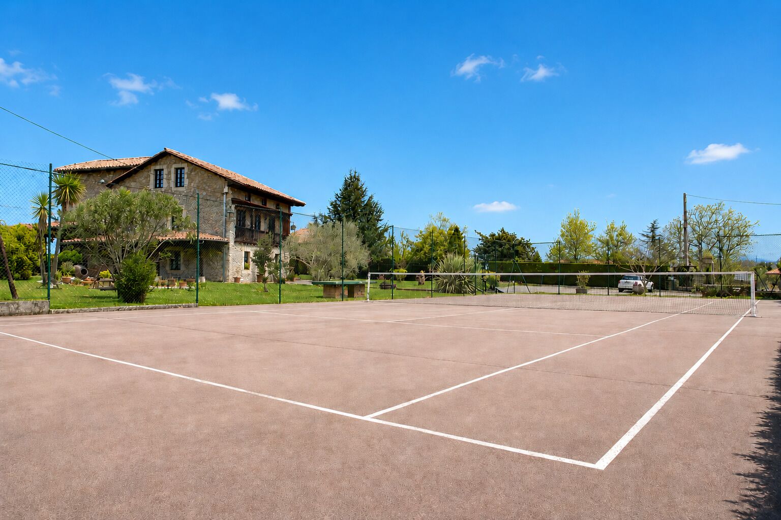 An outdoor tennis court with a stone building in the background.