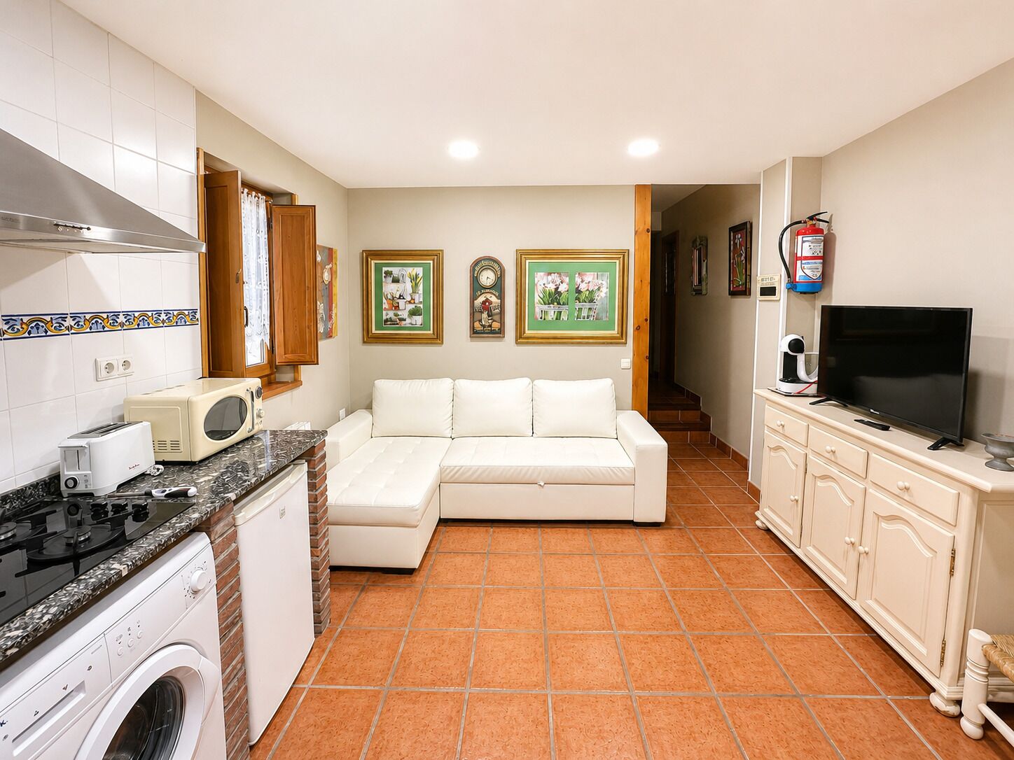 Una cocina compacta equipada con microondas, tostadora, estufa, lavadora y un sofá.