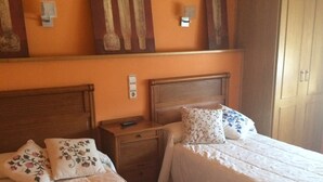 A hotel room with two beds, wooden headboards, and a wardrobe. - Hostal Mónica (Valle De Valdebezana)