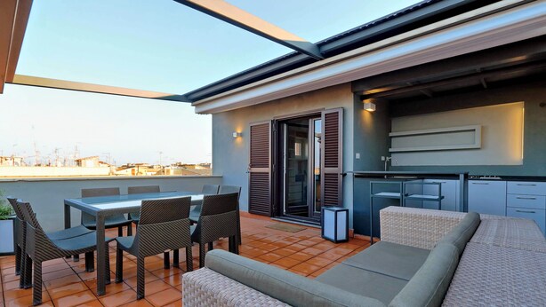 A modern outdoor patio with a dining area, seating, and a kitchen. - San Lorenzo (Rome)