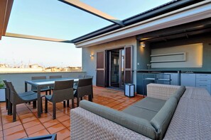 Une terrasse extérieure moderne comprenant un espace repas, des sièges et une cuisine.