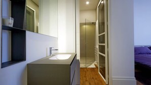 A modern bathroom with a large mirror, a sink, and a glass shower enclosure. - San Lorenzo (Rome)