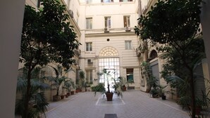 Un patio con plantas en macetas y una fuente central.