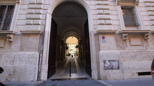 Una entrada imponente con un arco central que da paso a un edificio de arquitectura clásica.
