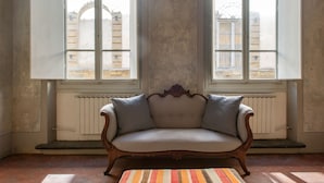 A room with a vintage sofa, large windows, and a radiator. - Ponte Vecchio Affresco (Florence)