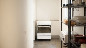 A kitchen with a built-in oven and a metal shelving unit with dishes. - Ponte Vecchio Affresco (Florence)