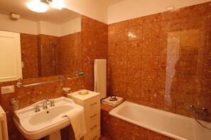 A bathroom with a sink, mirror, and bathtub.