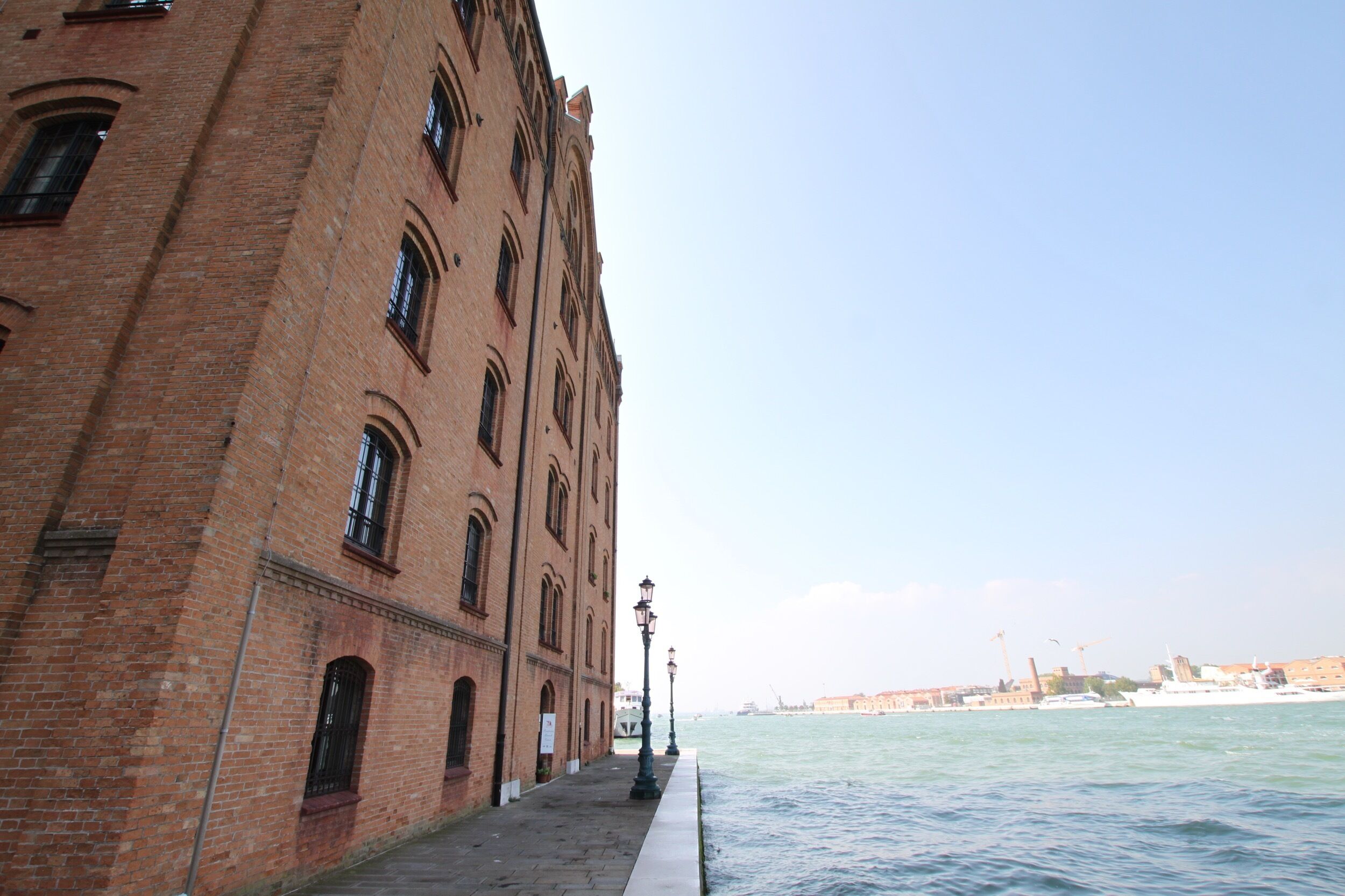 A brick building with arched windows and a waterfront view.