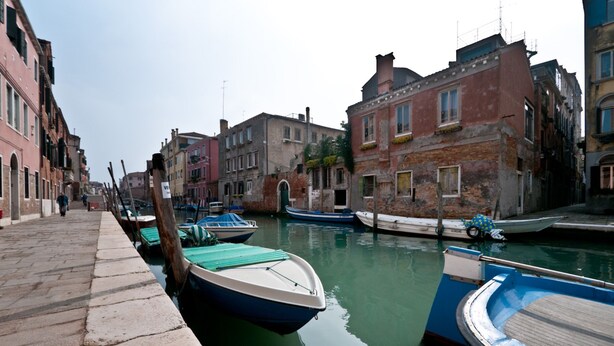 A canal with boats docked along the sides, surrounded by historic buildings. - San Marcuola Green (Venice)