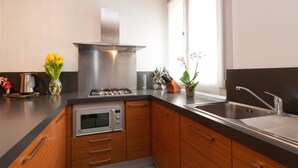 A modern kitchen with wooden cabinets, a stainless steel stove, and a sink. - San Marcuola Green (Venice)