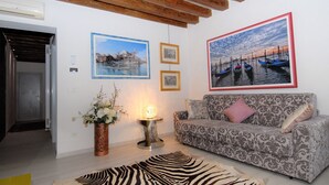 A living room with a patterned sofa, a zebra rug, and framed pictures on the wall. - San Marcuola Green (Venice)