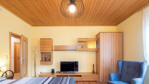 Une chambre à coucher avec un lit, une télévision, des meubles en bois et un fauteuil bleu.