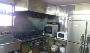 Een koelkast, een magnetron, een kookplaat, kookgerei, borden en bestek