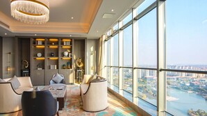 A modern living room with a large window, a chandelier, and a city view. - Ramada Plaza by Wyndham Nanxun (Huzhou)