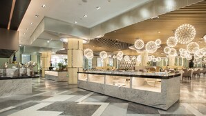 A modern hotel lobby with a marble reception desk, a central chandelier, and a patterned floor. - Ramada Plaza by Wyndham Nanxun (Huzhou)