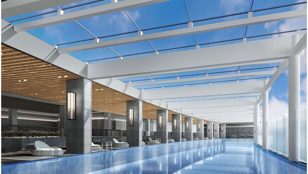 A modern indoor swimming pool with glass ceiling, seating areas, and a view of the sky. - Ramada Plaza by Wyndham Nanxun (Huzhou)