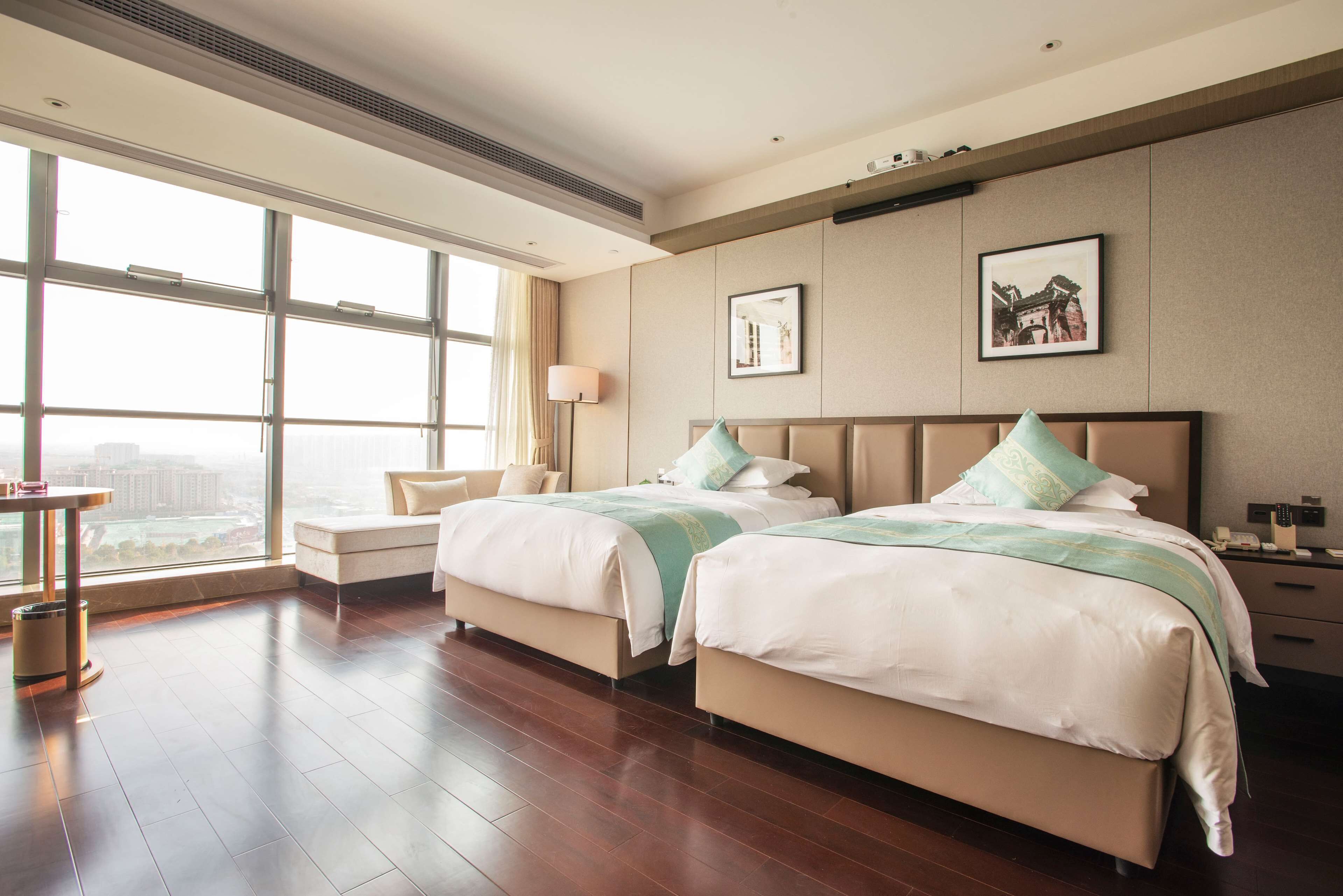 Een hotelkamer met twee bedden, een groot raam, een bureau en een stoel.