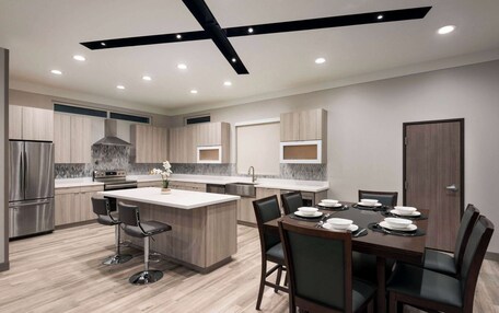 A modern kitchen with a central island, bar stools, and a dining table set for six.