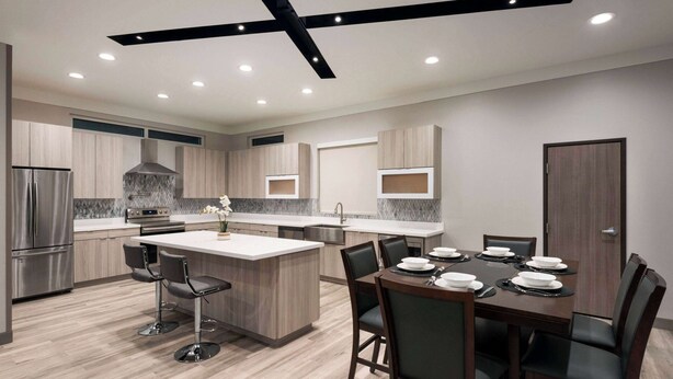 Una cocina moderna con una isla central, taburetes de bar y una mesa de comedor para seis personas.