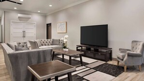 Una sala de estar moderna con un sofá modular, una mesa de centro, un televisor y un sillón gris.