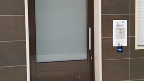En hotellentrél med en brun dörr, en glaspanel och en skylt som visar om det finns lediga rum.