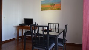 En matplats med ett bord och stolar, en tavla på väggen och en tv på ett stativ.