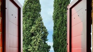 An open red door leading to a grassy area with trees and a view of the sky. - Tenuta Agricola Fraschiera (Massa Marittima)
