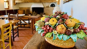 A dining area with a wooden table and chairs, a fireplace, and a fruit basket on the table. - Tenuta Agricola Fraschiera (Massa Marittima)