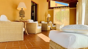 A cozy room with wicker furniture, a bed, and a window with curtains. - Tenuta Agricola Fraschiera (Massa Marittima)