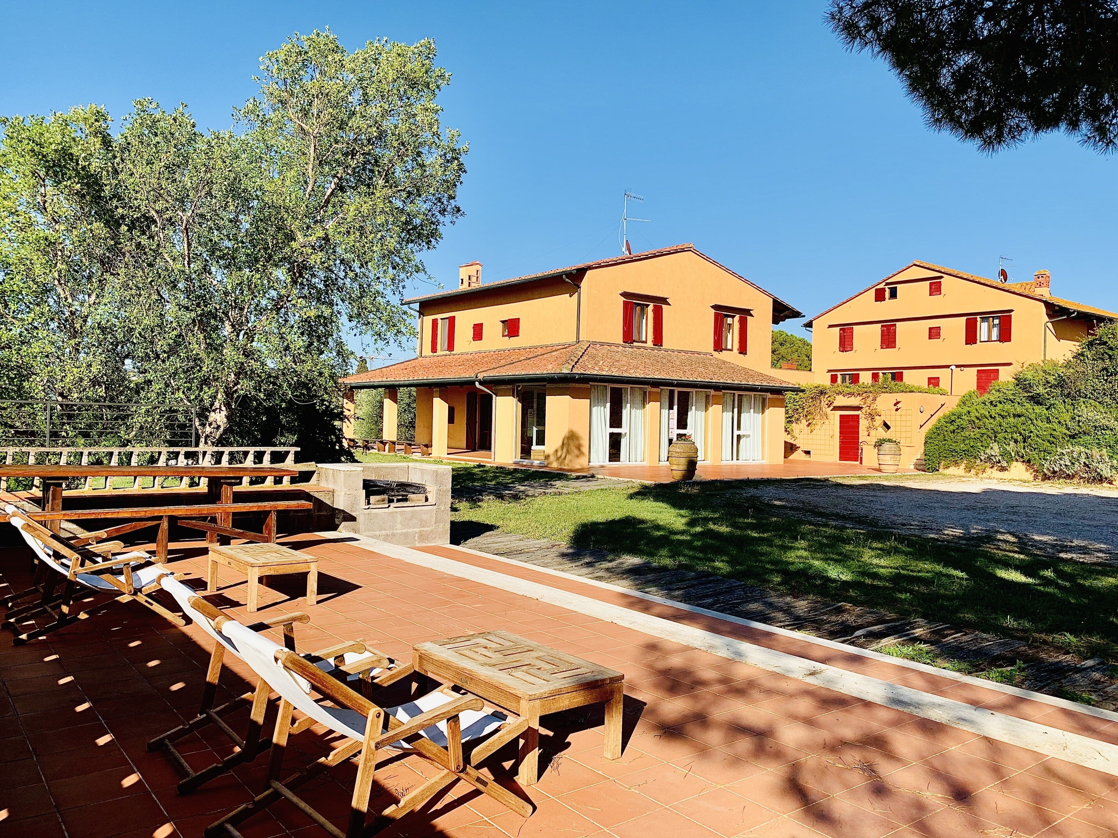 A courtyard with outdoor seating and a building with red shutters.