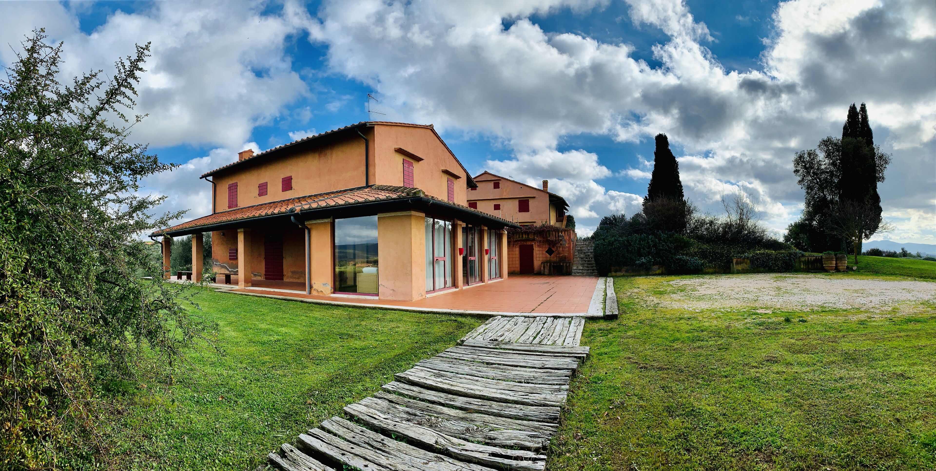 A two-story house with a wooden deck leading to the entrance.