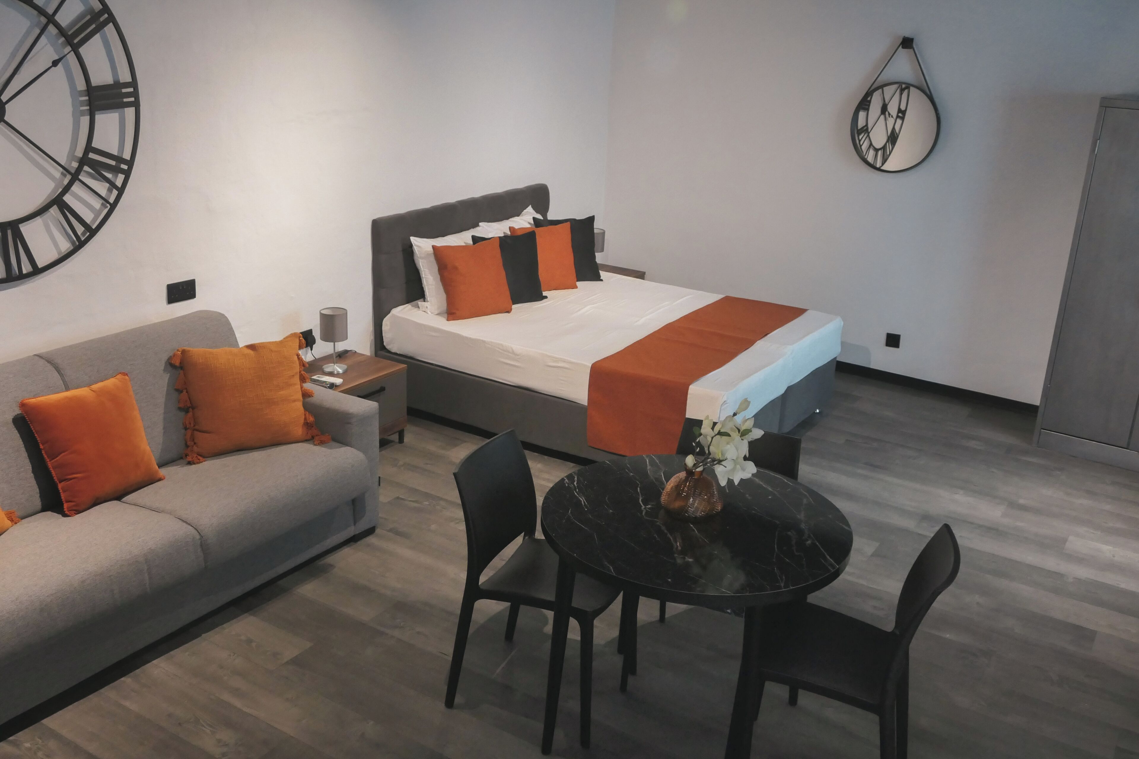 Una habitación de hotel moderna con una cama, un sofá, una mesa de comedor y sillas.