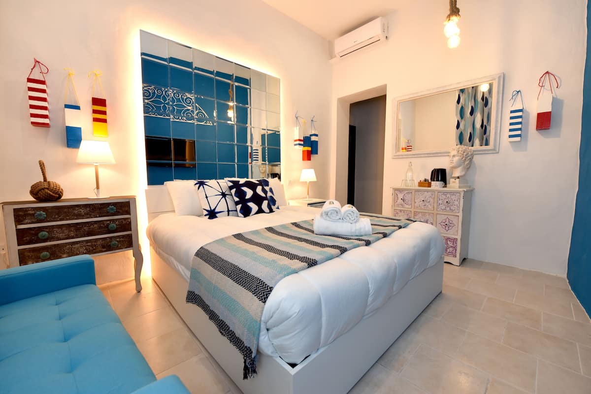 Un dormitorio moderno con una cama grande, un aparador, una tocador con espejo y una pared azul.