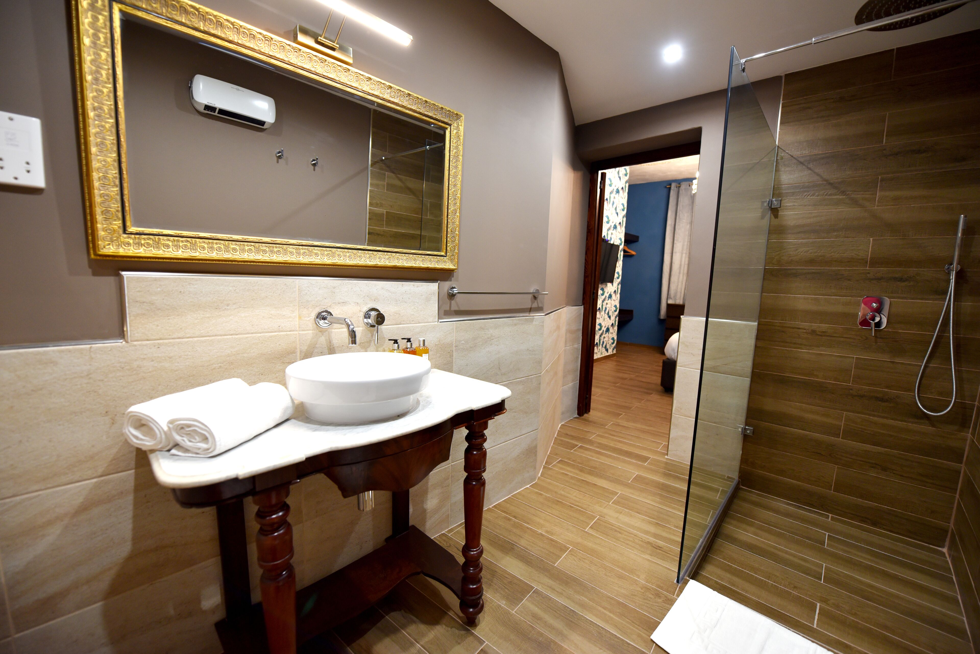 A bathroom with a large mirror, a sink, a shower, and a towel rack.