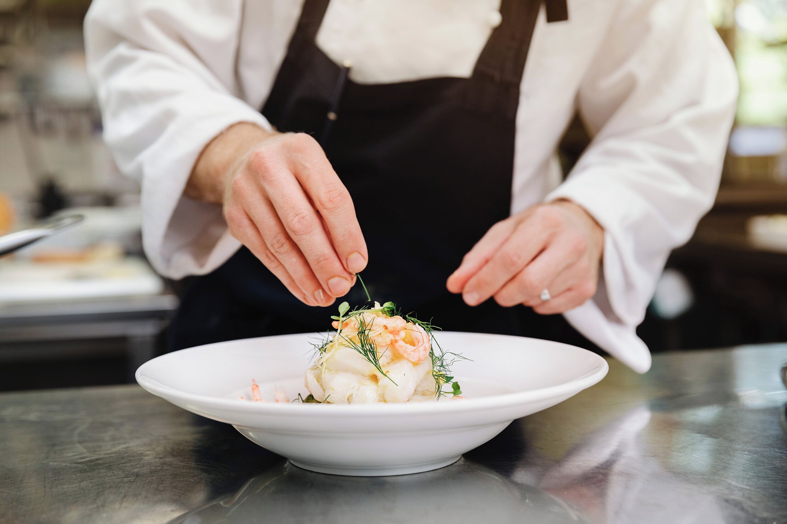 A chef preparing a dish on a white plate.
