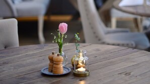 A cozy dining area with a wooden table, a vase with a pink flower, and a candle.