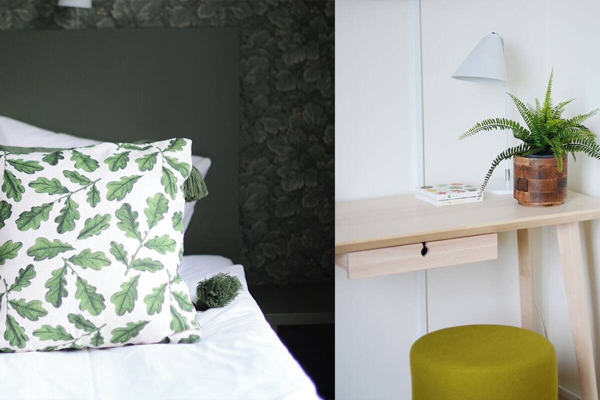 A neatly arranged bedroom with a bed, a bedside table with a lamp, and a potted plant.