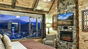 Un dormitorio con un ventanal grande, chimenea y vistas a la ciudad.