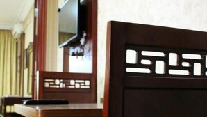 A hotel room with a wooden headboard, a flat-screen TV mounted on the wall, and framed pictures above the bed. - Rana Palace (Amman)