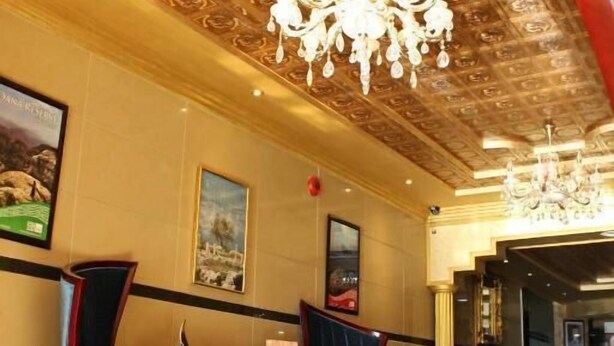 A lobby with a patterned ceiling, a chandelier, and seating areas. - Rana Palace (Amman)