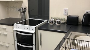 A modern kitchen with a black and white stove, a black toaster, and a sink with a dish rack. - Belfast Town House (Belfast)