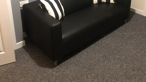A black leather sofa with striped pillows against a grey wall, a framed picture of a brick wall, and a door in the background. - Belfast Town House (Belfast)