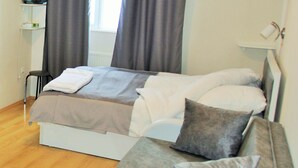 Ein ordentlich eingerichtetes Schlafzimmer mit einem Bett, einem Schlafsofa und einem Nachttisch.