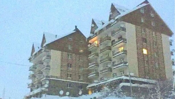 Ein mehrstöckiges Hotel mit schneebedeckten Balkonen und traditioneller Architektur.
