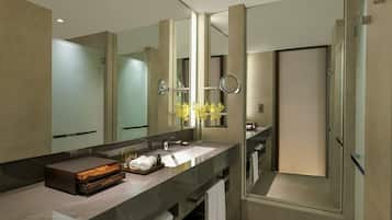 A modern bathroom with a large mirror, a glass shower enclosure, and a marble countertop.