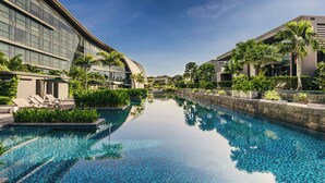 A modern hotel with a swimming pool, lounge chairs, and palm trees. - Dusit Thani Laguna Singapore (Singapore)